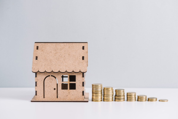 monedas-apiladas-cerca-de-modelo-casa-en-fondo-blanco